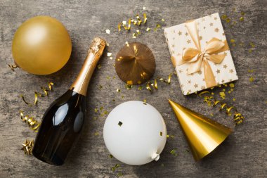 Renkli arka planda şampanya şişesi hediye paketi kurdeleleri ve konfetilerin düz kompozisyonu vardı. Düz konum, üst görünüm tatil konsepti.