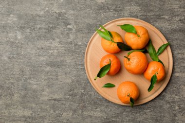 Taze kesilmiş mandalinalar ve renkli arka planda yuvarlak tabaklar. Yemek ve içecek malzemeleri hazırlanıyor. Sağlıklı beslenme teması üst görünüm kopyalama alanı.