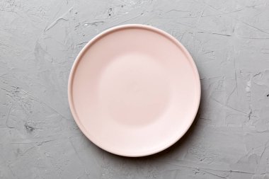 Çimento arka planındaki boş pembe tabağın üst görüntüsü. Tasarımın için boş boşluk.