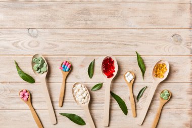 Renkli arka planda tahta kaşıkta vitamin ve mineral haplarının üst görünümü. Muhtelif ilaç haplarının en üst görüntüsü. Beslenme takviyesi sağlık ürünleri.