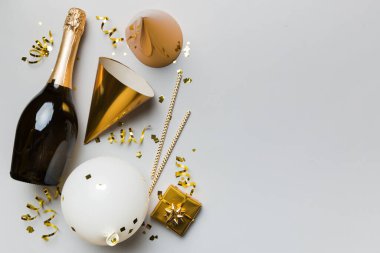 Renkli arka planda şampanya şişesi hediye paketi kurdeleleri ve konfetilerin düz kompozisyonu vardı. Düz konum, üst görünüm tatil konsepti.