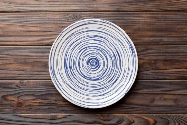 Ahşap zemindeki boş renkli tabağın üst görünümü. Tasarımın için boş boşluk.