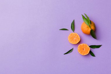 Renkli arkaplanda yeşil yaprakları, üst görünümü, metin için alanı olan bir sürü olgun mandalina..