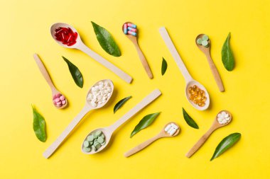 Renkli arka planda tahta kaşıkta vitamin ve mineral haplarının üst görünümü. Muhtelif ilaç haplarının en üst görüntüsü. Beslenme takviyesi sağlık ürünleri.