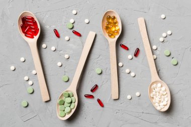 Renkli arka planda tahta kaşıkta vitamin ve mineral haplarının üst görünümü. Muhtelif ilaç haplarının en üst görüntüsü. Beslenme takviyesi sağlık ürünleri.