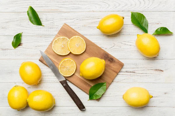 Kesme tahtasındaki taze ve olgun limonlar için fotokopi alanı olan üst manzara. Sağlıklı yemek geçmişi. Limon ve limon dilimlerinin, sıkacağı ve bıçak renginde arka planı çok zarif..