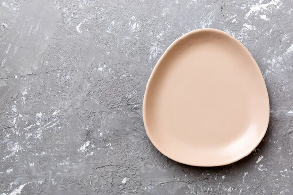 Çimento arka planındaki boş pembe tabağın üst görüntüsü. Tasarımın için boş boşluk.