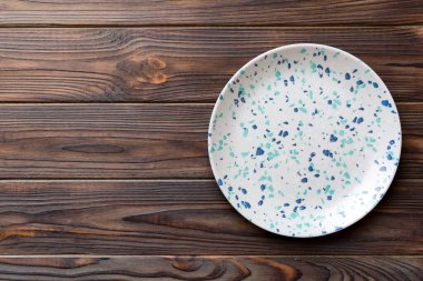 Ahşap zemindeki boş renkli tabağın üst görünümü. Tasarımın için boş boşluk.