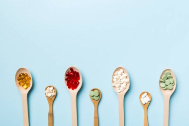 Renkli arka planda tahta kaşıkta vitamin ve mineral haplarının üst görünümü. Muhtelif ilaç haplarının en üst görüntüsü. Beslenme takviyesi sağlık ürünleri.
