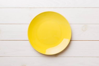 Ahşap arka planda boş sarı tabağın üst görüntüsü. Tasarımın için boş boşluk.