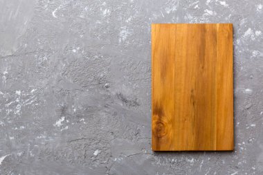 Çimento arka planında ahşap kesim tahtasının üst görüntüsü. Tasarımın için boş boşluk.