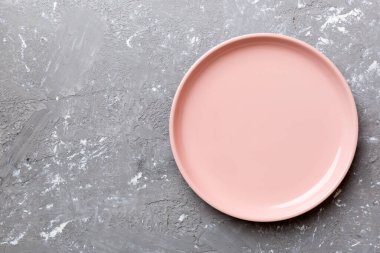 Çimento arka planındaki boş pembe tabağın üst görüntüsü. Tasarımın için boş boşluk.