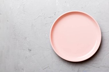 Çimento arka planındaki boş pembe tabağın üst görüntüsü. Tasarımın için boş boşluk.