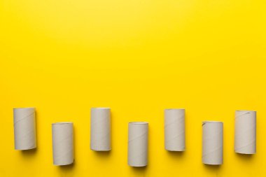 Boş tuvalet kağıdı ruloları ve renk arkaplanı üzerine metin için alanı olan düz bir kompozisyon. Kraft kağıdı veya kartondan yapılmış metal kapaklı geri dönüşümlü kağıt tüp.