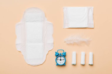 Alarm saatini hijyenik kadın tamponları ve regl pedleri ile çalıyor. Tıbbi konsept kadın kritik günler ve regl dönemi. Kadın günlük hijyen. Boşluğu kopyala.