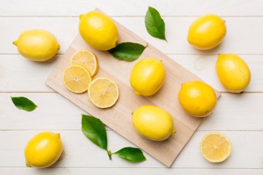 Kesme tahtasındaki taze ve olgun limonlar için fotokopi alanı olan üst manzara. Sağlıklı yemek geçmişi. Limon ve limon dilimlerinin zarif arkaplanı daha sıkan renkli arkaplan.