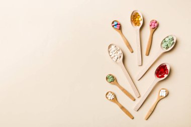Renkli arka planda tahta kaşıkta vitamin ve mineral haplarının üst görünümü. Muhtelif ilaç haplarının en üst görüntüsü. Beslenme takviyesi sağlık ürünleri.