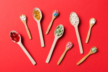 Renkli arka planda tahta kaşıkta vitamin ve mineral haplarının üst görünümü. Muhtelif ilaç haplarının en üst görüntüsü. Beslenme takviyesi sağlık ürünleri.