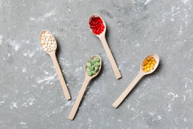 Renkli arka planda tahta kaşıkta vitamin ve mineral haplarının üst görünümü. Muhtelif ilaç haplarının en üst görüntüsü. Beslenme takviyesi sağlık ürünleri.