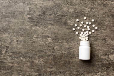 Renkli arka planda plastik şişede çok renkli haplar ve kapsüller, kopyalama alanı. Çeşitli ilaç tabletleri ve haplar, vitamin ve besin takviyeleri kavramı.