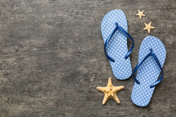 Renkli arka planda parmak arası terlikleri ve deniz kabuğu olan düz bir kompozisyon. Metin üstü görünümü için boşluk.