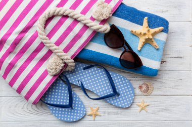 Plaj aksesuarları renkli arka plan yaz seyahati konseptinde düz bir görünüm sergiliyordu. İçinde deniz yıldızı ve deniz kabuğu olan bir çanta. Üst görünüm.