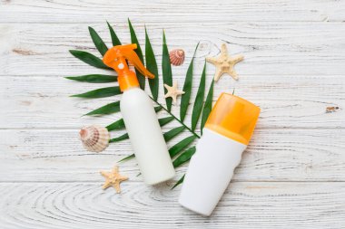 Güneş kremi şişesi. Güneş korumalı krem ve tropik yeşil yapraklı deniz kabukları olan bir şişe..