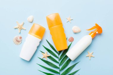 Güneş kremi şişesi. Güneş korumalı krem ve tropik yeşil yapraklı deniz kabukları olan bir şişe..