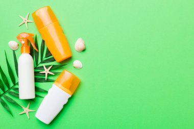Güneş kremi şişesi. Güneş korumalı krem ve tropik yeşil yapraklı deniz kabukları olan bir şişe..