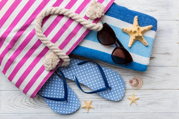Plaj aksesuarları renkli arka plan yaz seyahati konseptinde düz bir görünüm sergiliyordu. İçinde deniz yıldızı ve deniz kabuğu olan bir çanta. Üst görünüm.