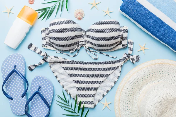 Kadın mayo ve plaj aksesuarları renkli arka plan yaz seyahati konseptine düz bir görünüm kazandırıyordu. Bikini mayo, hasır şapka ve deniz topuklu ayakkabı. Üst görünümü kopyala.