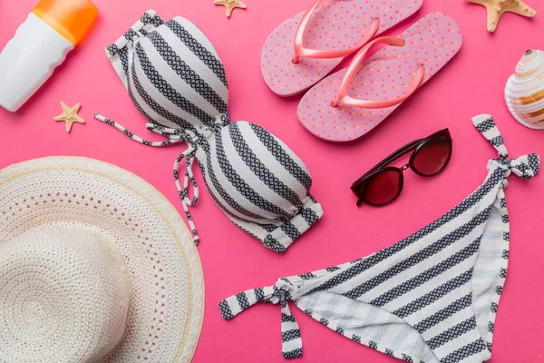 Kadın mayo ve plaj aksesuarları renkli arka plan yaz seyahati konseptine düz bir görünüm kazandırıyordu. Bikini mayo, hasır şapka ve deniz topuklu ayakkabı. Üst görünümü kopyala.