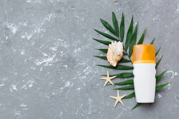Güneş kremi şişesi. Güneş korumalı krem ve tropik yeşil yapraklı deniz kabukları olan bir şişe..