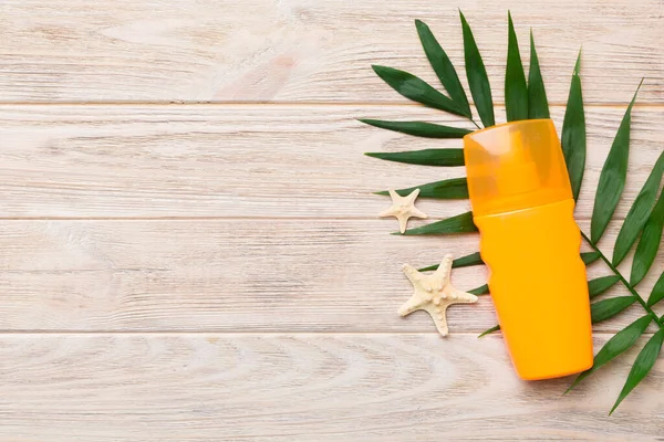 Güneş kremi şişesi. Güneş korumalı krem ve tropik yeşil yapraklı deniz kabukları olan bir şişe..