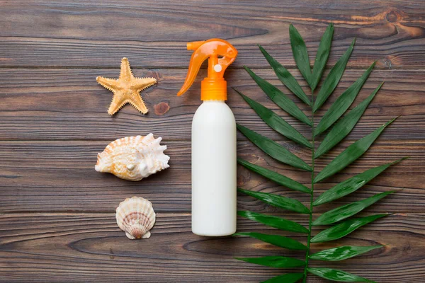 Güneş kremi şişesi. Güneş korumalı krem ve tropik yeşil yapraklı deniz kabukları olan bir şişe..