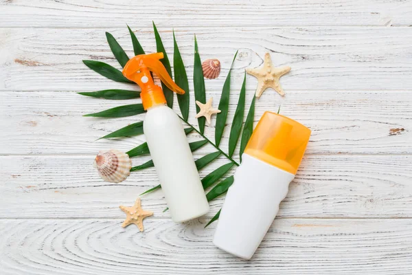 Güneş kremi şişesi. Güneş korumalı krem ve tropik yeşil yapraklı deniz kabukları olan bir şişe..