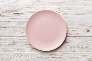 Ahşap arka planda boş pembe tabağın üst görüntüsü. Tasarımın için boş boşluk.