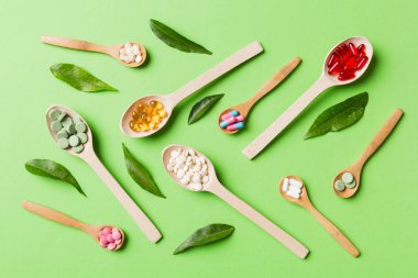 Renkli arka planda tahta kaşıkta vitamin ve mineral haplarının üst görünümü. Muhtelif ilaç haplarının en üst görüntüsü. Beslenme takviyesi sağlık ürünleri.
