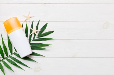 Güneş kremi şişesi. Güneş korumalı krem ve tropik yeşil yapraklı deniz kabukları olan bir şişe..
