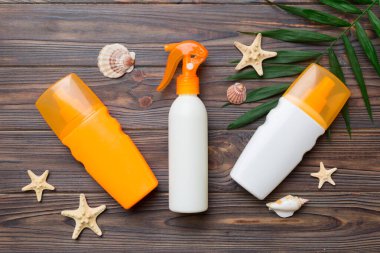 Güneş kremi şişesi. Güneş korumalı krem ve tropik yeşil yapraklı deniz kabukları olan bir şişe..