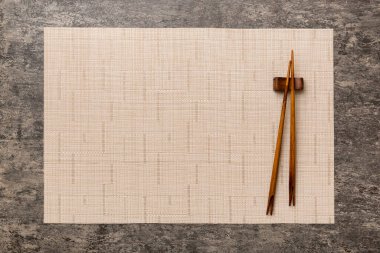Çimento arka planında iki çubuk ve bambu paspas. Üst görünüm, alanı kopyala.