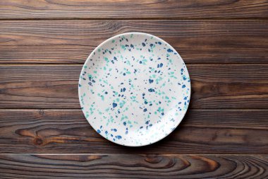 Ahşap zemindeki boş renkli tabağın üst görünümü. Tasarımın için boş boşluk.