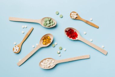 Renkli arka planda tahta kaşıkta vitamin ve mineral haplarının üst görünümü. Muhtelif ilaç haplarının en üst görüntüsü. Beslenme takviyesi sağlık ürünleri.
