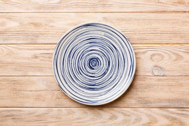 Ahşap zemindeki boş renkli tabağın üst görünümü. Tasarımın için boş boşluk.