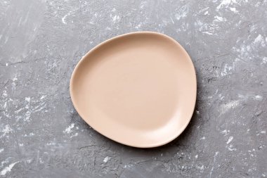 Çimento arka planındaki boş pembe tabağın üst görüntüsü. Tasarımın için boş boşluk.