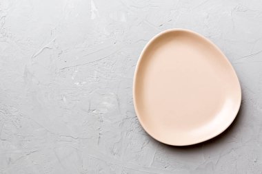 Çimento arka planındaki boş pembe tabağın üst görüntüsü. Tasarımın için boş boşluk.