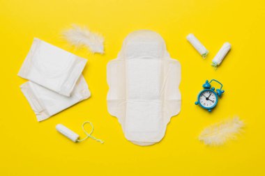 Alarm saatini hijyenik kadın tamponları ve regl pedleri ile çalıyor. Tıbbi konsept kadın kritik günler ve regl dönemi. Kadın günlük hijyen. Boşluğu kopyala.