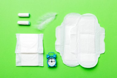 Alarm saatini hijyenik kadın tamponları ve regl pedleri ile çalıyor. Tıbbi konsept kadın kritik günler ve regl dönemi. Kadın günlük hijyen. Boşluğu kopyala.