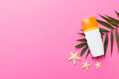 Güneş kremi şişesi. Güneş korumalı krem ve tropik yeşil yapraklı deniz kabukları olan bir şişe..