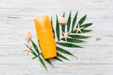 Güneş kremi şişesi. Güneş korumalı krem ve tropik yeşil yapraklı deniz kabukları olan bir şişe..